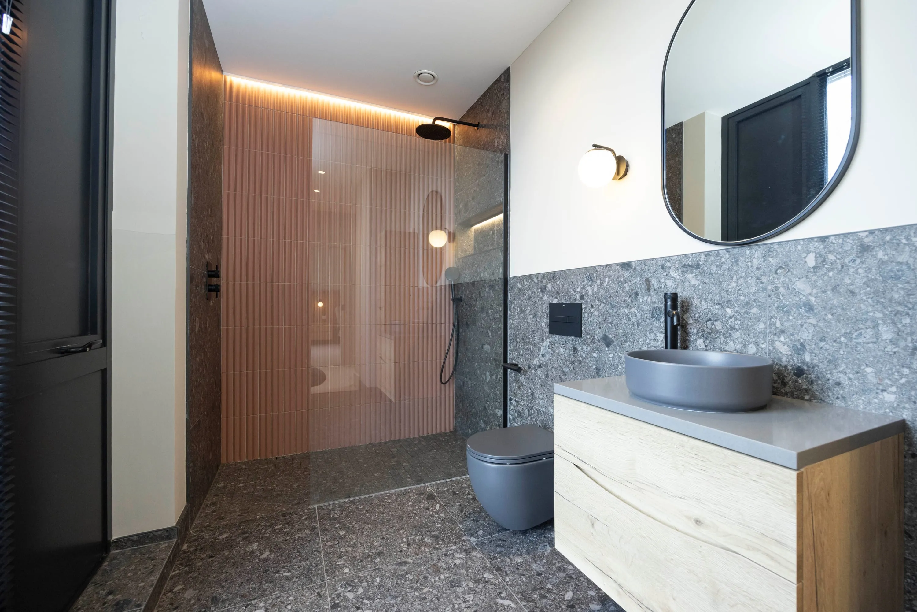 Principal en suite with terrazzo tiles, oak vanity and oval mirror