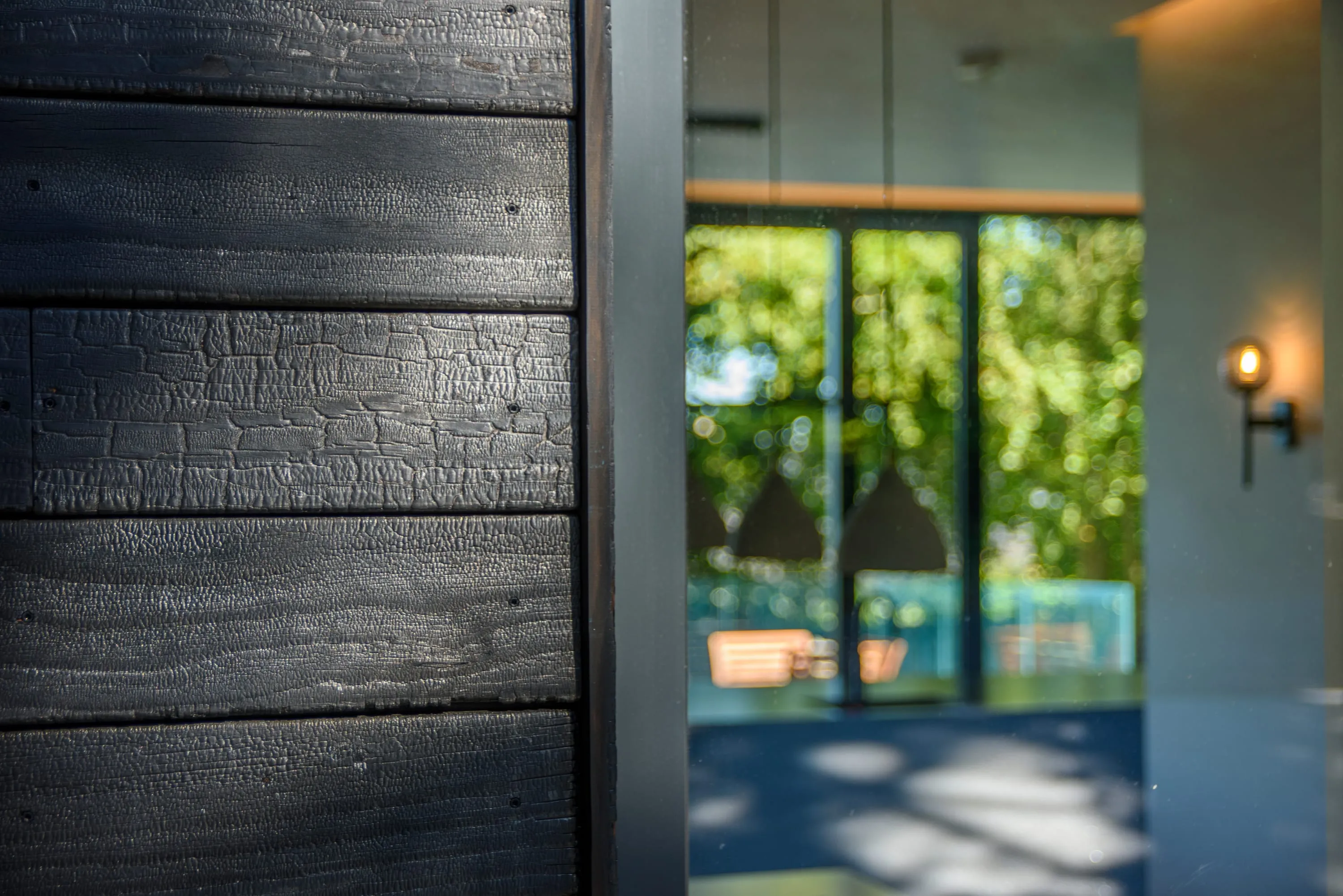 Close-up of the charred timber texture beside a glazed door