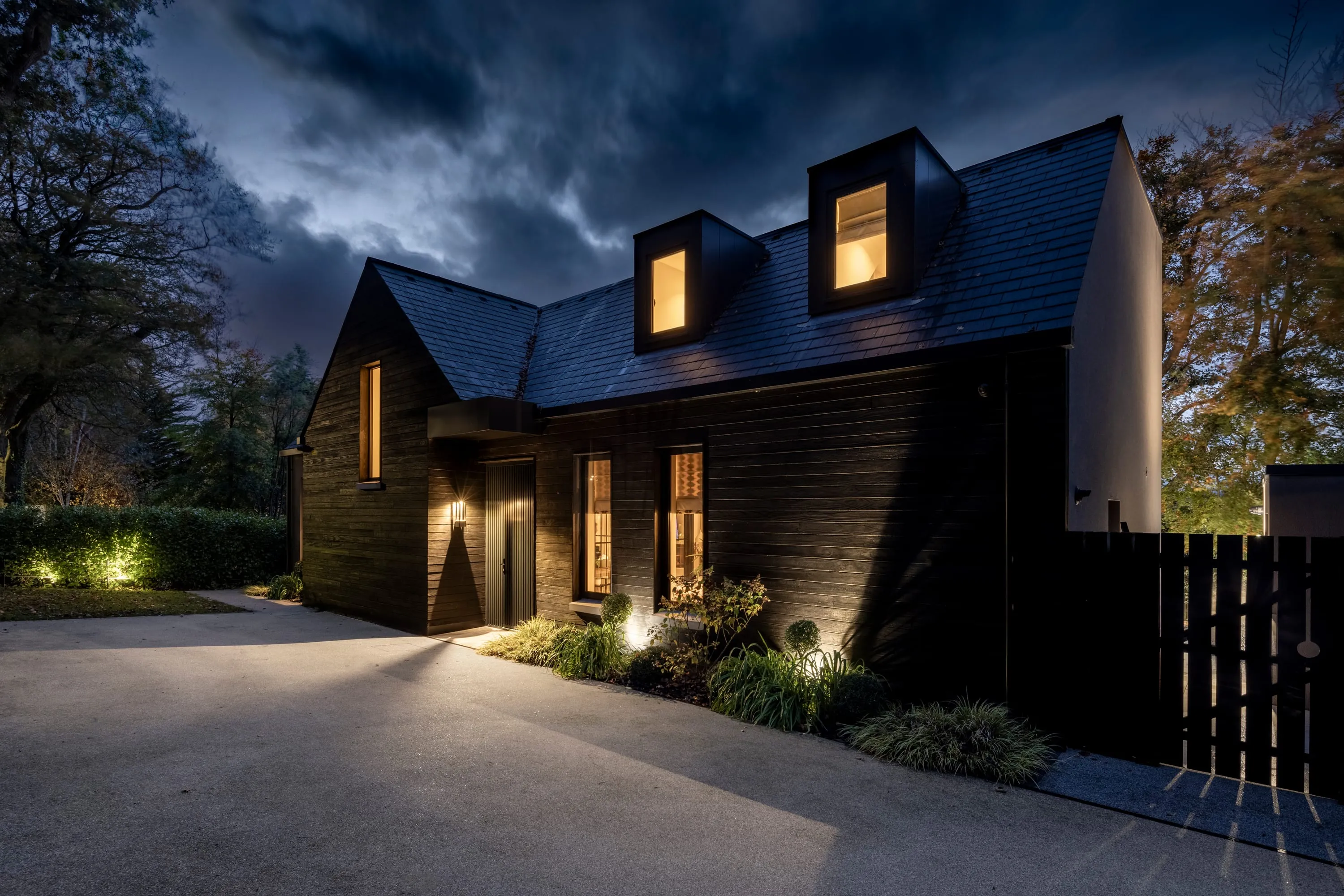 Front elevation at dusk with warm light in the dormer windows