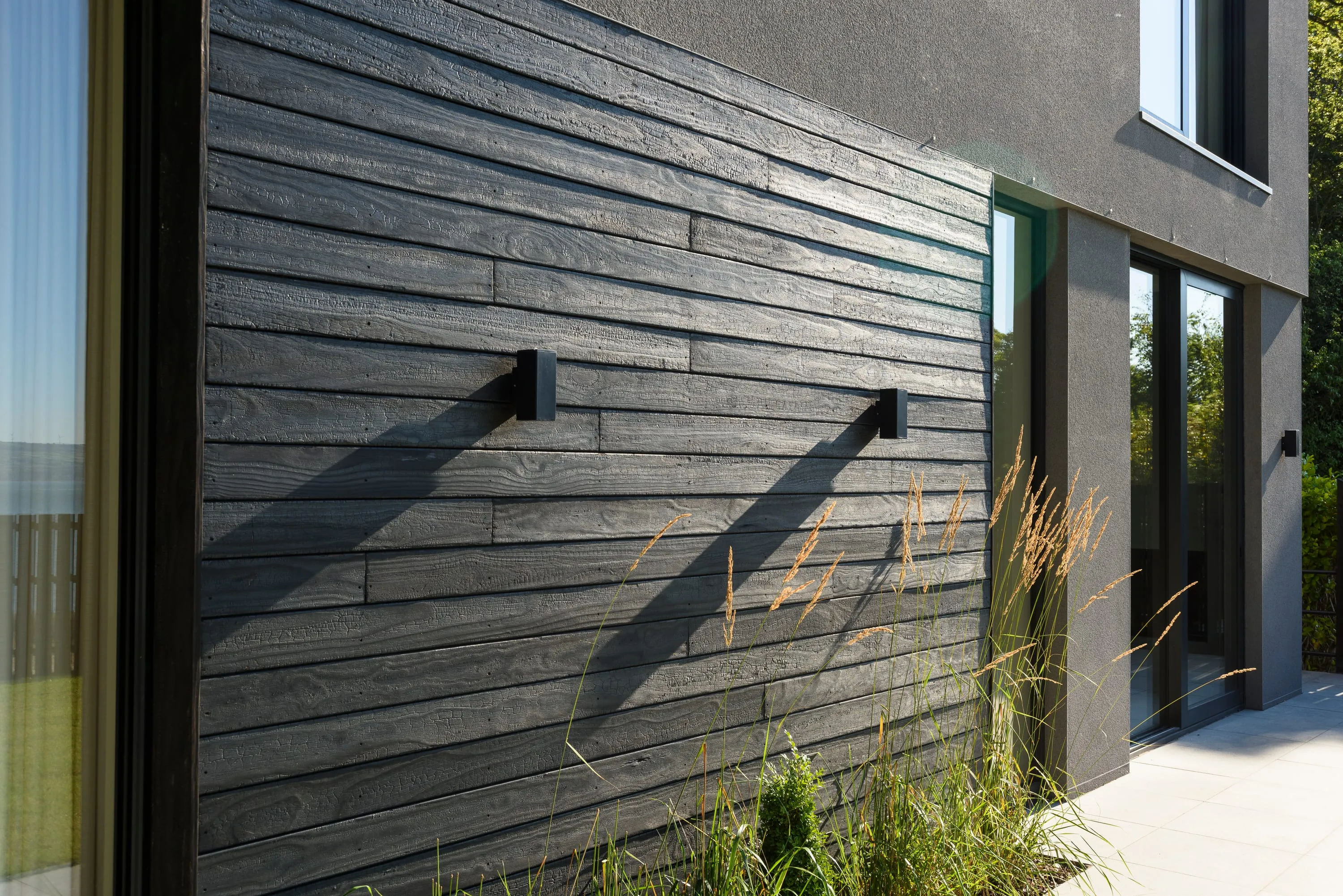 Horizontal scorched larch cladding and black-framed windows in daylight