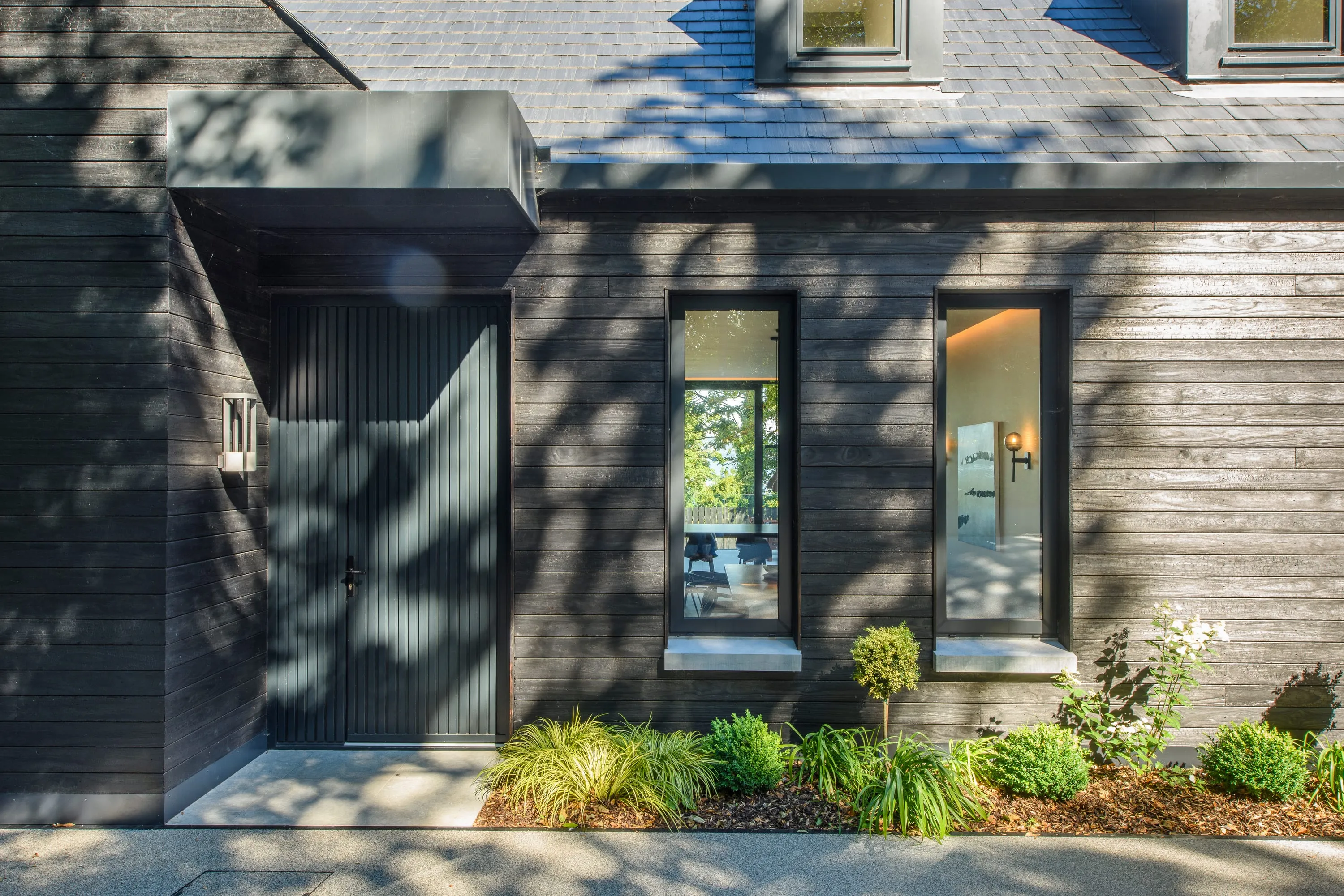 Front door canopy with vertical timber boarding and planting