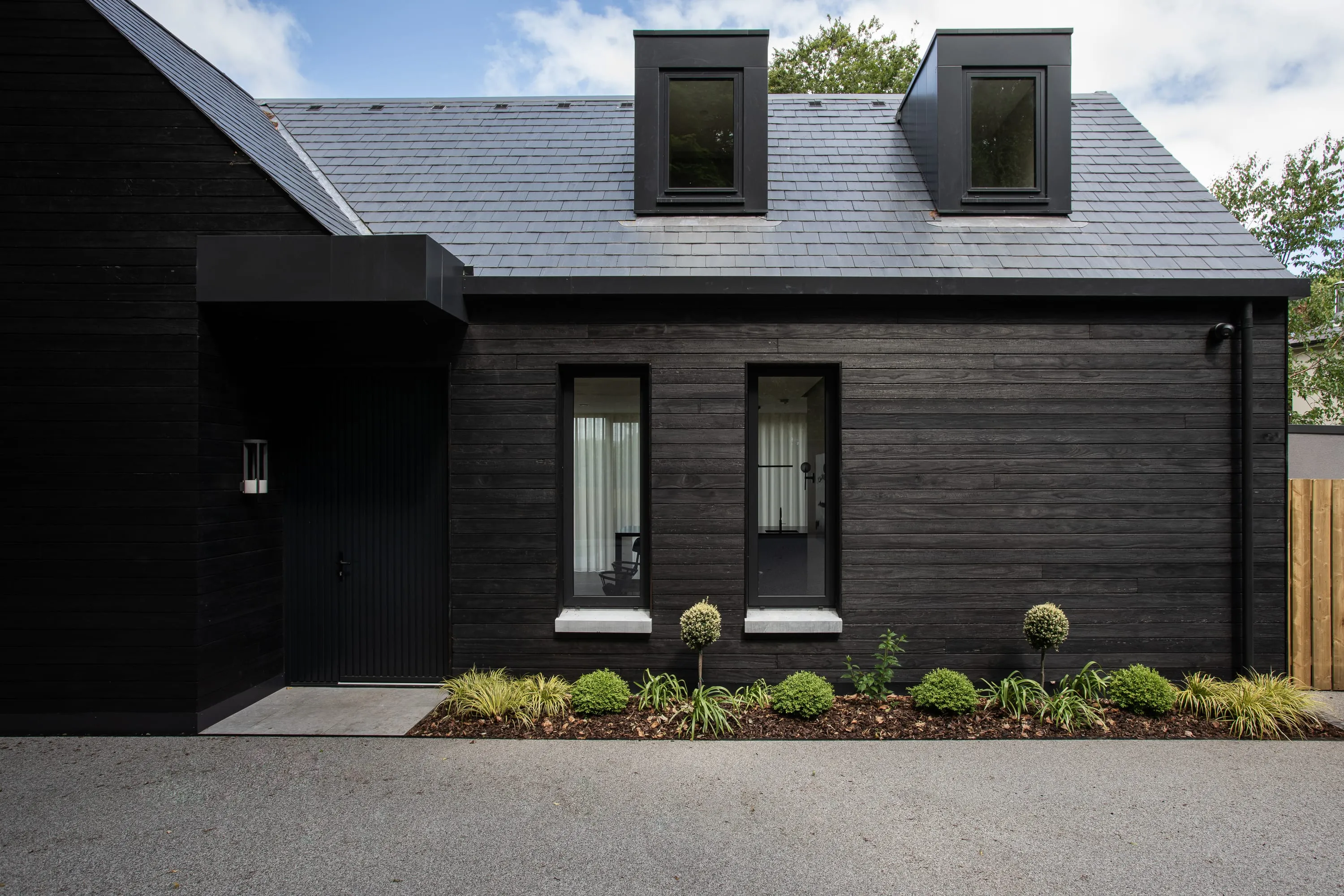 Front of the house from the driveway with clipped planting
