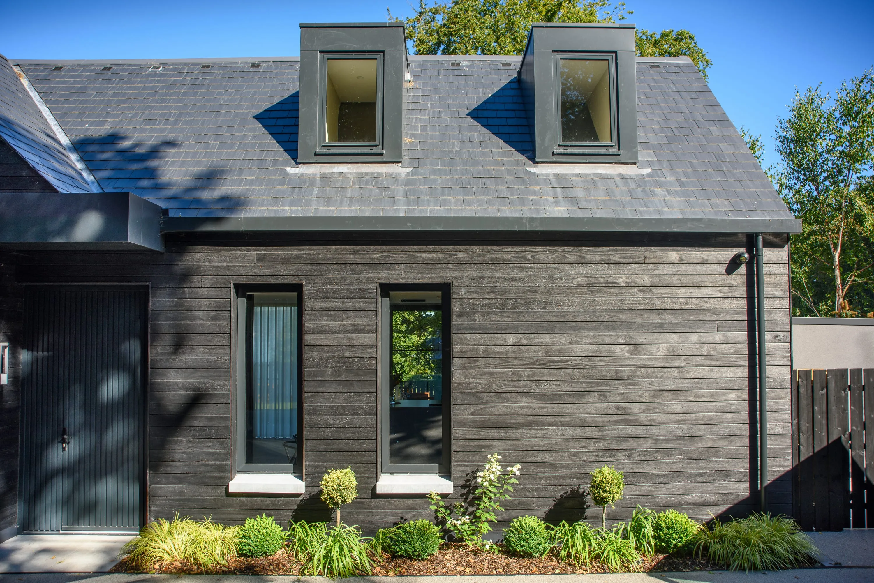 Front elevation with dormer windows and timber cladding in sunlight