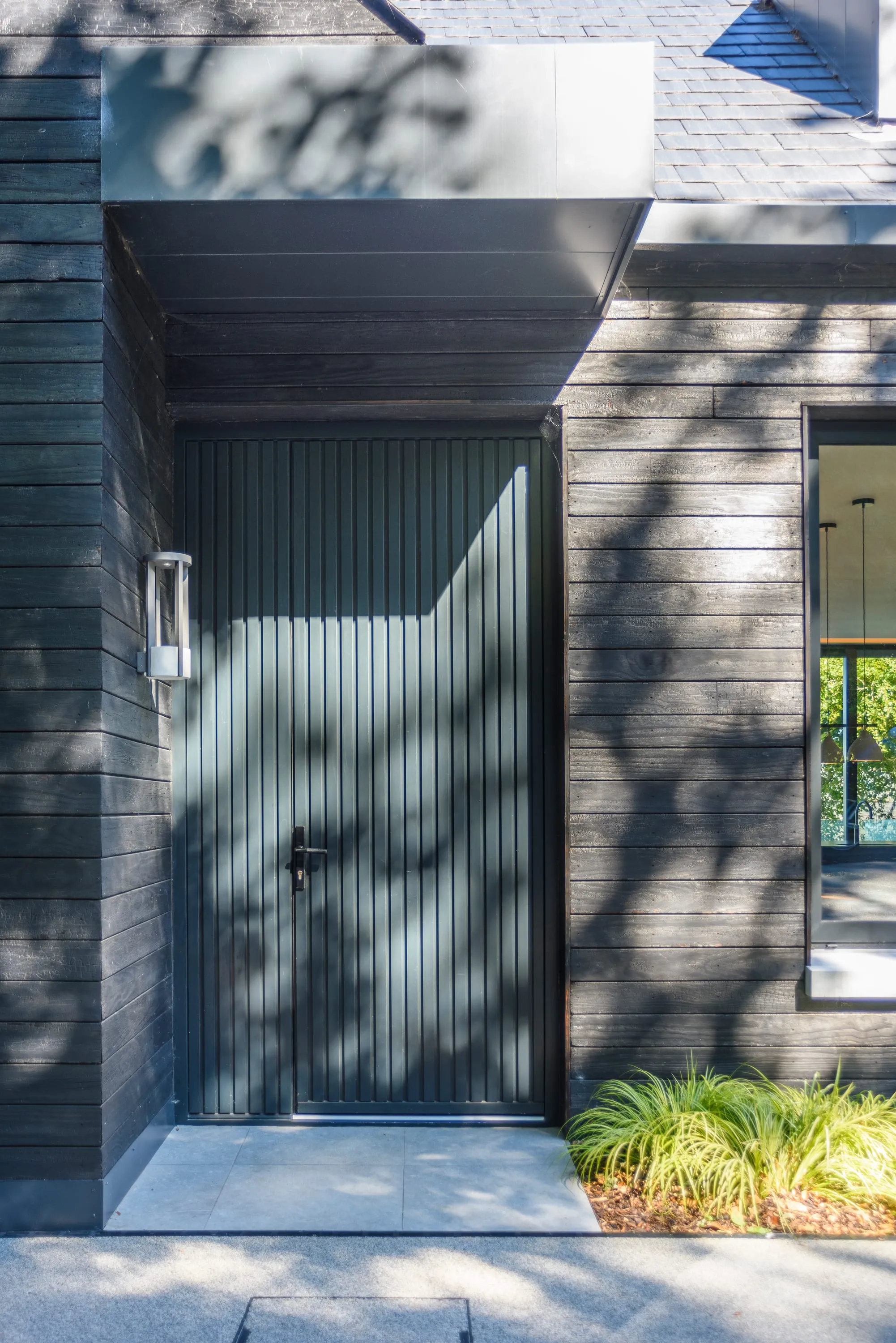 Front door and entrance canopy in dappled sunlight