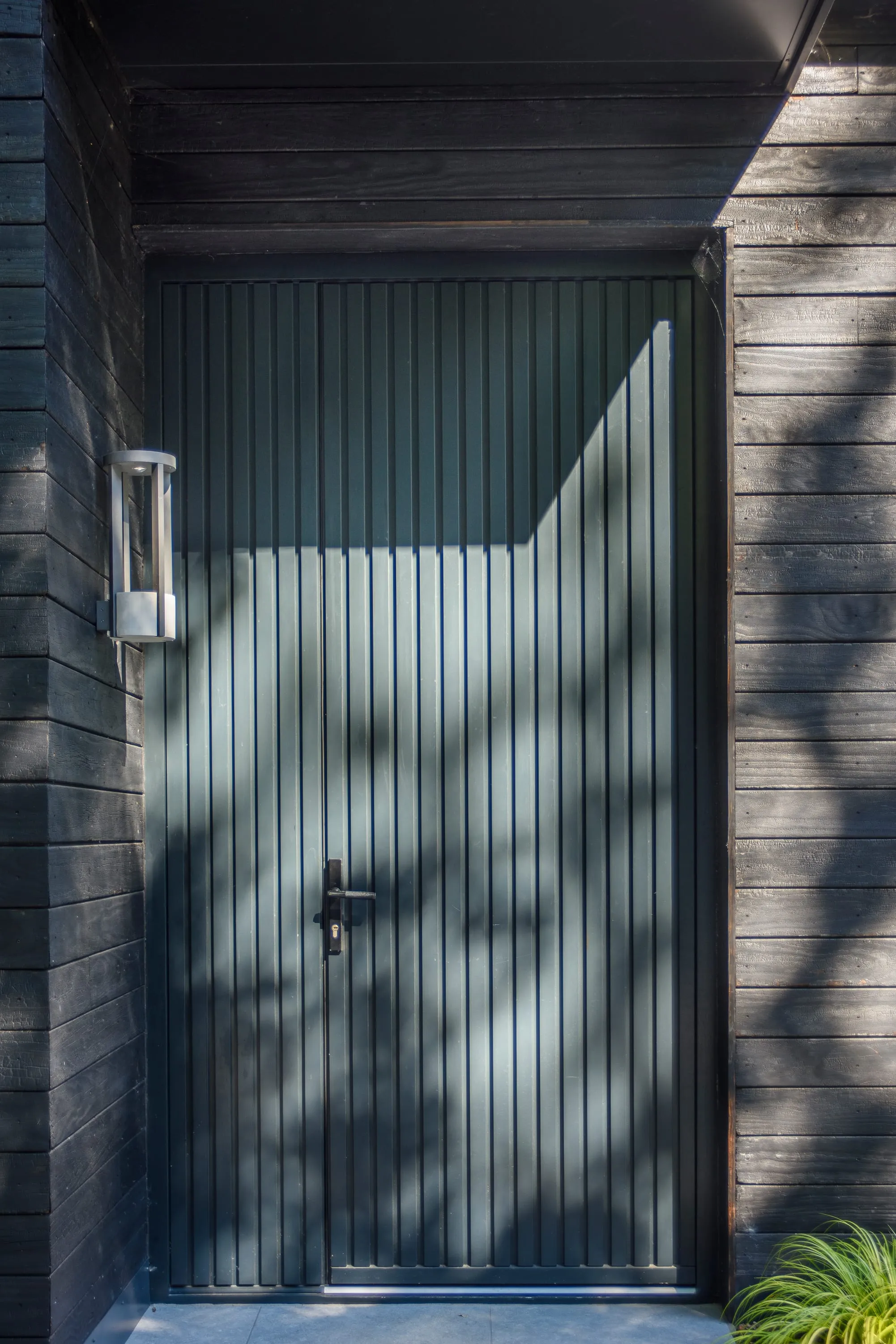 The vertical-boarded black front door