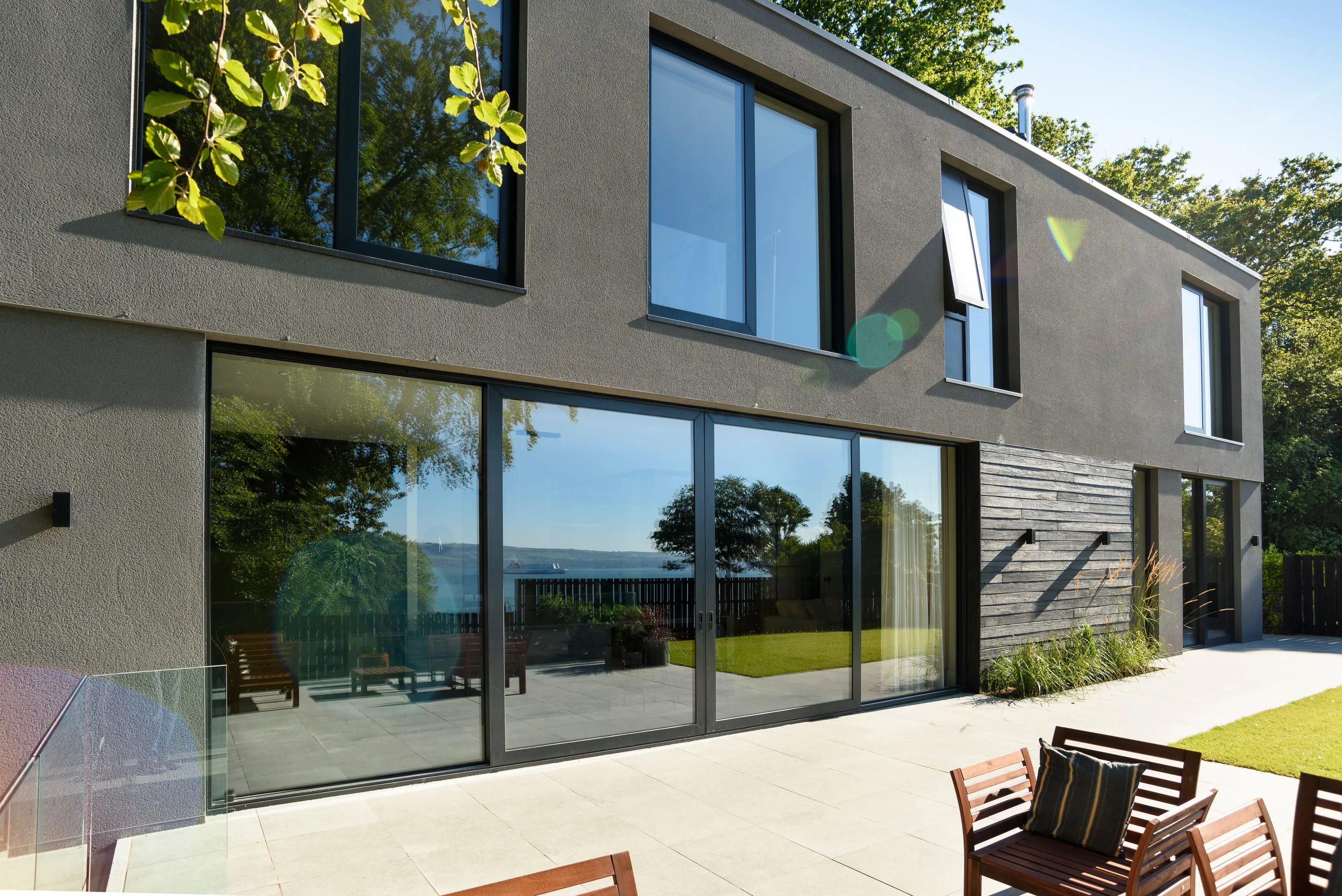Rear elevation with full-height glazing reflecting the garden