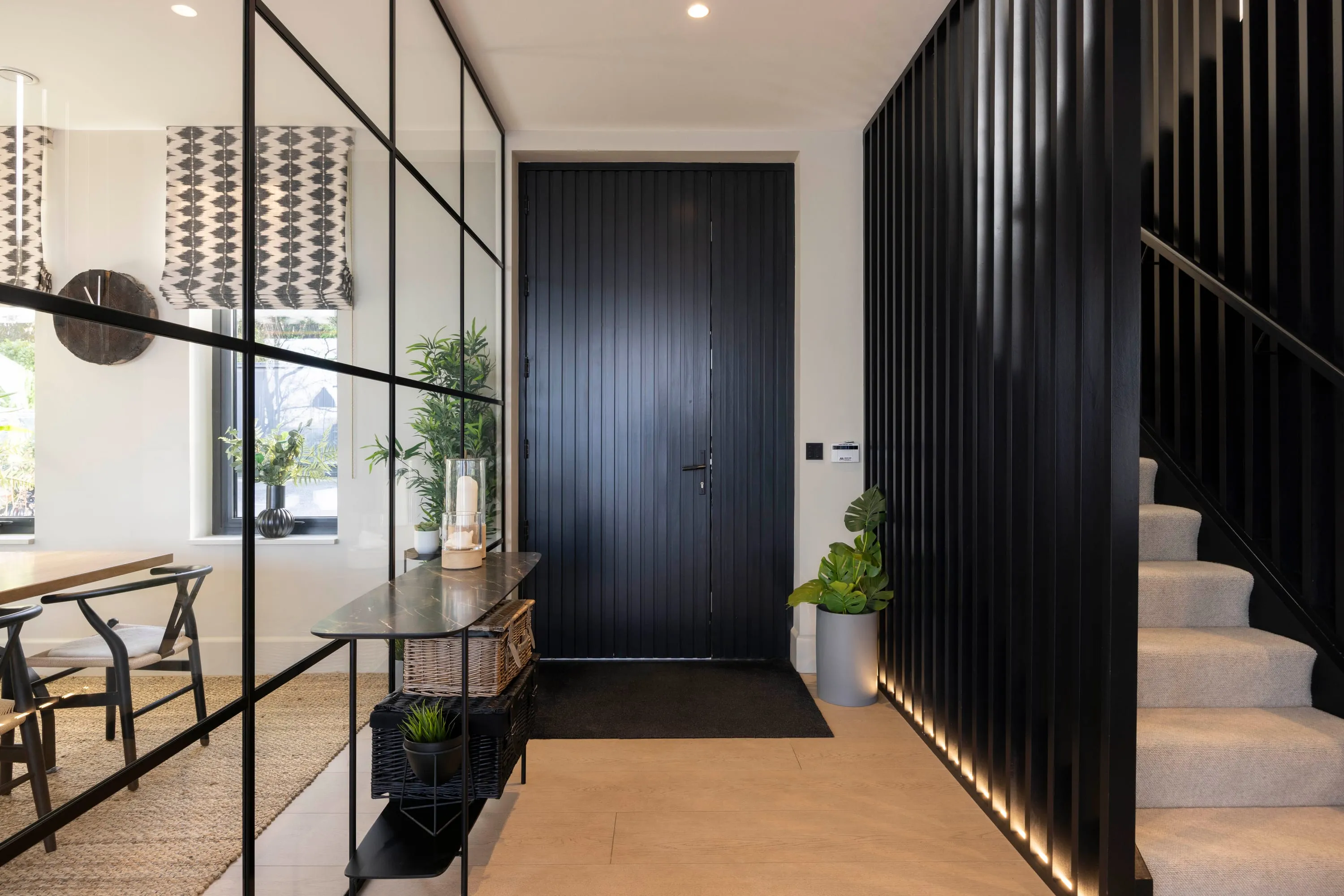 Entrance hall with the black front door and slatted timber staircase screen