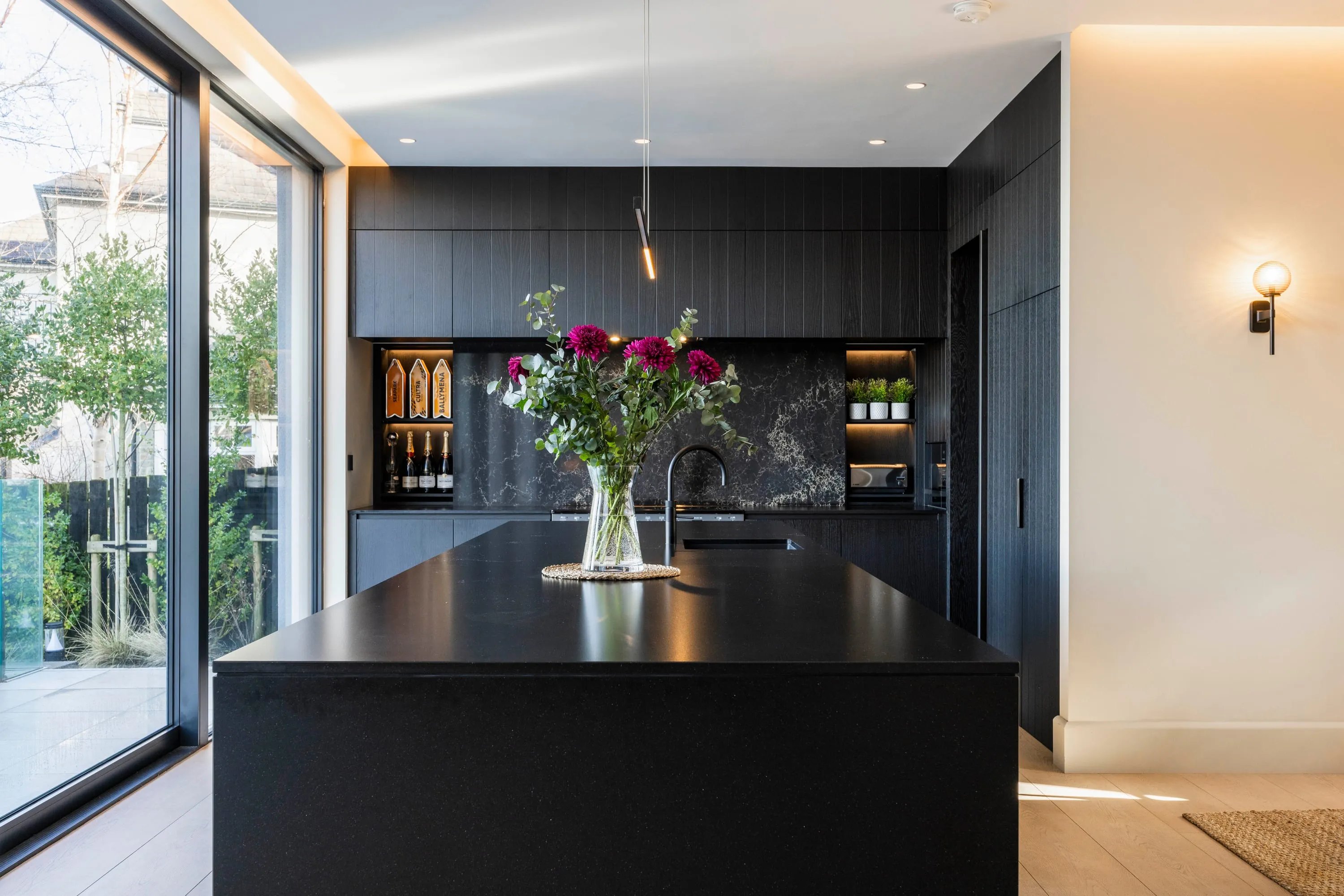 Black kitchen island with marble splashback and wine store