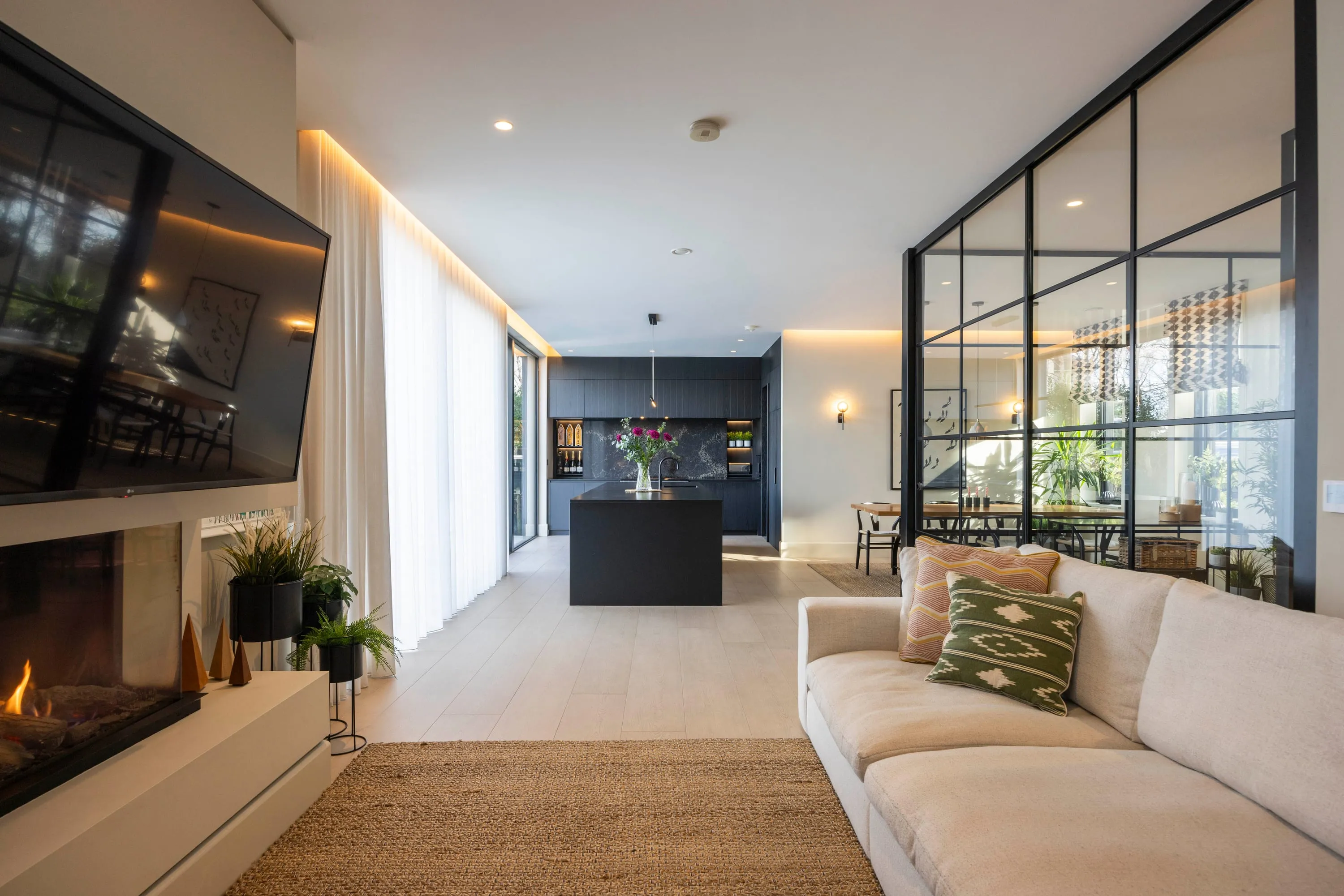 Open-plan living space with the fireplace, sofa and glazed screen