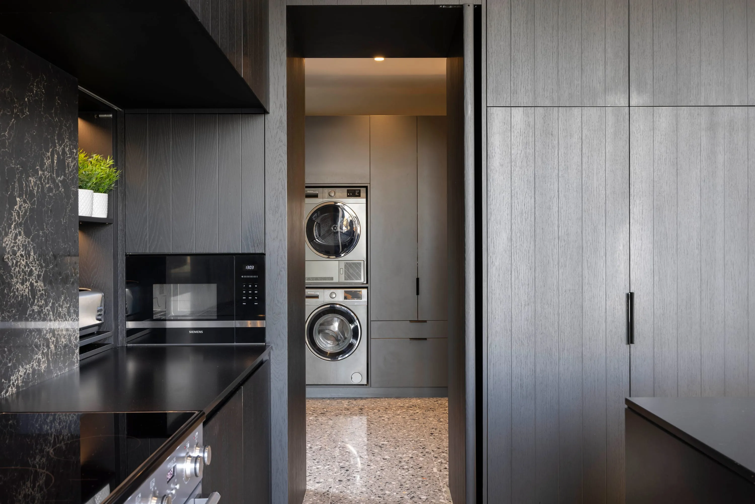 Utility room with stacked washer and dryer and dark cabinetry